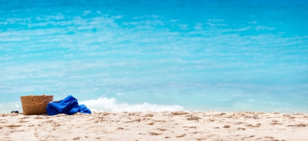 Panorama of a tropical beach with straw bag and towel on a sandの写真素材