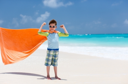 Little boy playing superhero at a tropical beachの写真素材