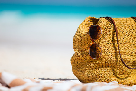 Close up of a straw bag, sun glasses and towel on a tropical beachの写真素材