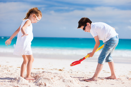 Brother and sister making sand castle at tropical beachの写真素材