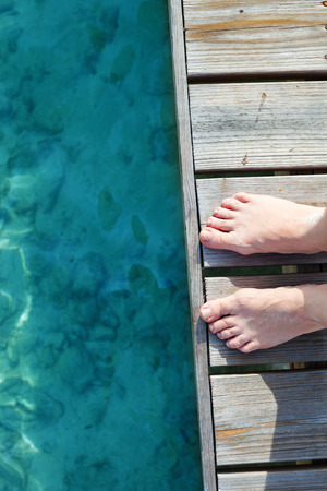 Woman legs close up at wooden jetty by the seaの写真素材