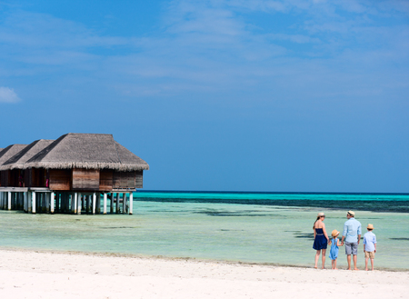 Tropical beach landscape with a beautiful family of four on summer vacationの写真素材