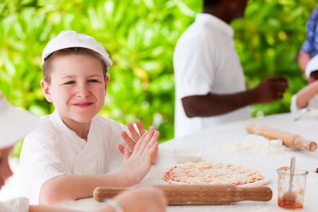 Cute boy dressed as chef making pizza on masterclassの写真素材