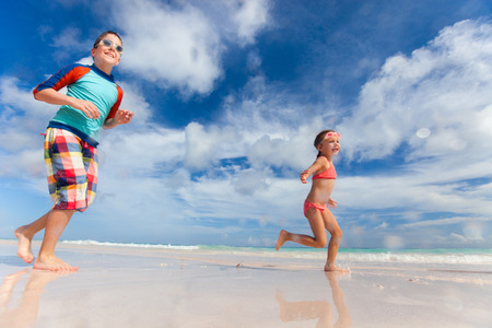 Happy kids having fun running and jumping at beach on summer vacationの写真素材