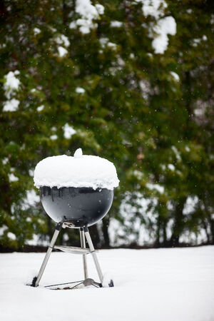 Black barbeque grill covered with snow outdoors on winter dayの写真素材