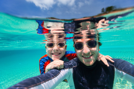 Split above and underwater photo of father and son swimmingの写真素材