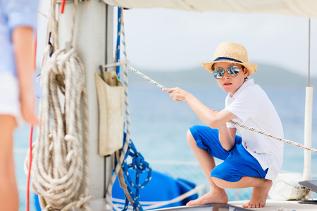 Cute teenage boy enjoying sailing on a luxury catamaran or yachtの写真素材