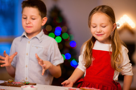 Two kids baking gingerbread cookies at home on Christmas eveの写真素材