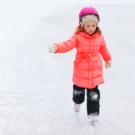 Adorable little girl outdoors on beautiful winter day ice skatingの写真素材