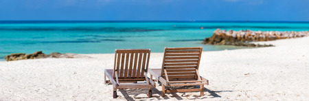 Panorama of a wooden lounge chairs on a beautiful tropical beach at Maldivesの写真素材