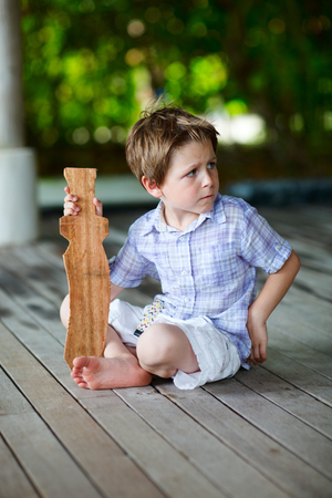 Little boy playing outdoors with wooden swordの写真素材