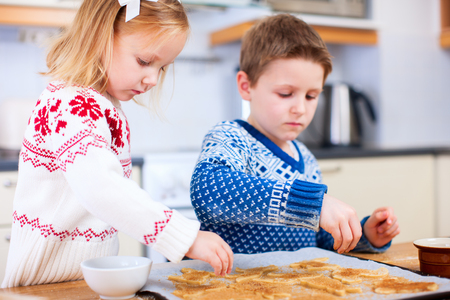 Kids wearing warm sweaters baking cookies in house kitchen on winter dayの写真素材