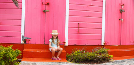 Adorable little girl outdoors against colorful house in Caribbeanの写真素材