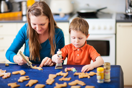 Young mother and son in home kitchen making cookiesの写真素材