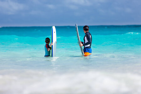 Father and son in ocean with boogie boards waiting for a waveの写真素材
