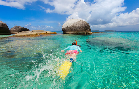 Young woman wearing sun protection swimwear snorkeling in turquoise tropical waterの写真素材