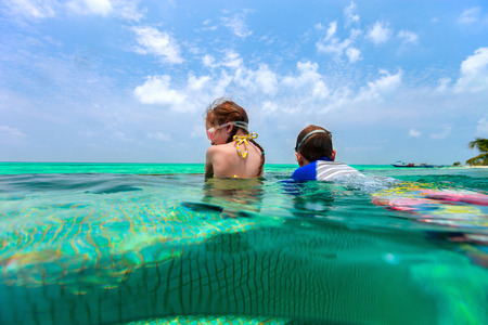 Split above and underwater photo of adorable kids having fun in swimming pool on summer vacationの写真素材