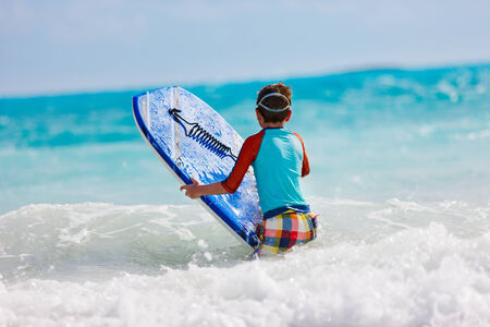Little boy on vacation having fun surfing on boogie boardの写真素材