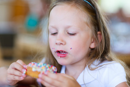 Adorable little girl enjoying eating donut at cafeの写真素材