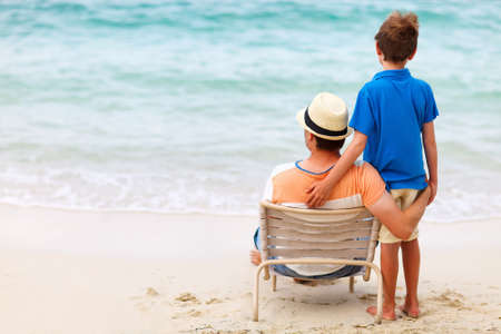 Back view of father and son at beachの写真素材
