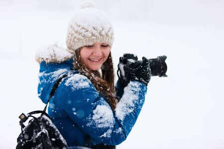 Portrait of beautiful woman with camera on winter snow dayの写真素材