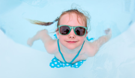 Adorable little girl at swimming pool having fun during summer vacationの写真素材