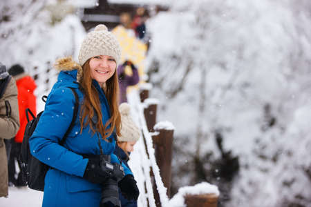 Portrait of beautiful woman with camera on winter snow dayの写真素材