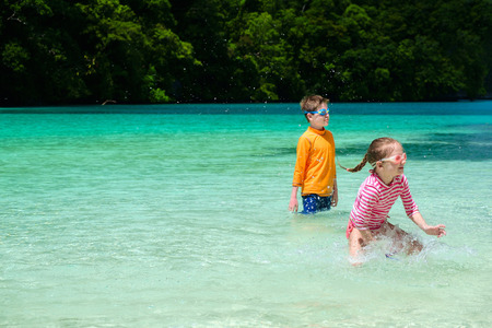 Two kids playing at at shallow water during summer vacationの写真素材