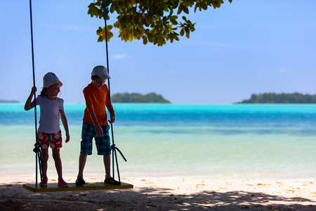 Kids having fun swinging at beach on summer vacationの写真素材