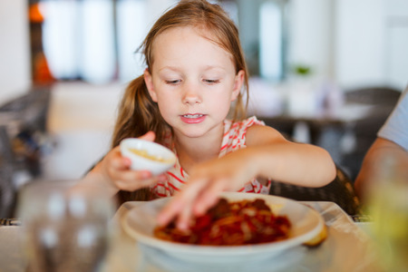 Portrait of adorable little girl eating lunch at restaurantの写真素材