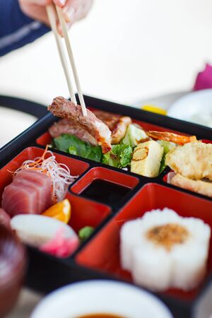Delicious Japanese lunch bento box with rice, fish sashimi, omelet, meat and vegetablesの写真素材