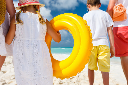 Back view of a happy family at tropical beach on summer vacationの写真素材