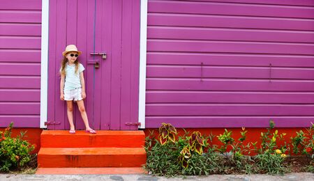 Adorable little girl outdoors against colorful house in Caribbeanの写真素材