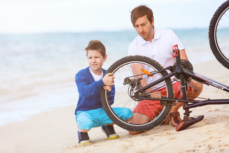 Teenage boy and his father repairing bicycle outdoors at summerの写真素材