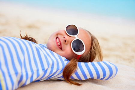 Adorable little girl lying on a beach towel during summer vacationの写真素材