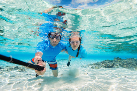 Underwater photo of a couple snorkeling in ocean and making selfie with stickの写真素材
