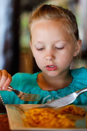 Adorable little girl eating breakfast in restaurantの写真素材