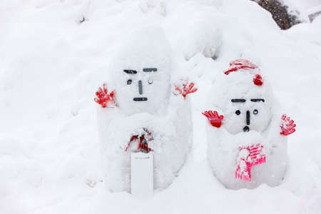 Two Japanese snowmen with red gloves in the snow on cold winter dayの写真素材