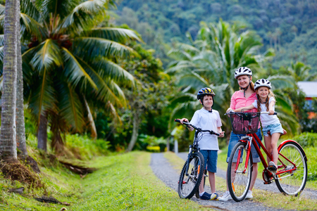 Family of mother and kids biking at tropical settings having fun togetherの写真素材