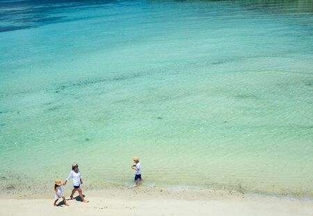 Aerial view of a tropical coast with mother and kids enjoying beach vacationの写真素材