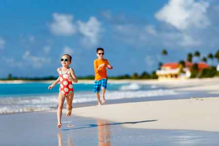 Kids having fun at tropical beach during Caribbean summer vacation playing together at shallow waterの写真素材