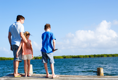 Family father and kids fishing together from wooden jettyの写真素材