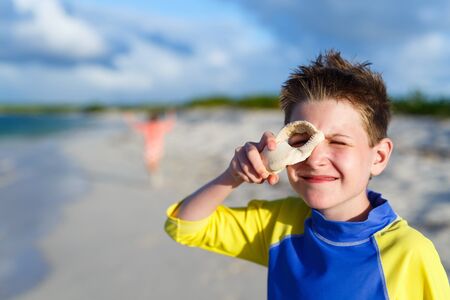 Happy boy with shell at tropical beach during summer vacationの写真素材