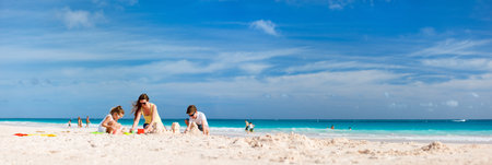 Mother and kids making sand castle at tropical beachの写真素材
