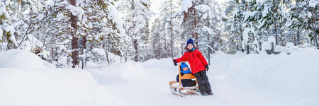 Panorama of adorable little girl and cute boy outdoors on beautiful winter day having fun playing in snowの写真素材