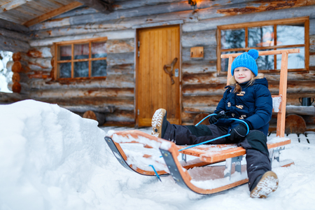 Little girl outdoors on beautiful winter day in front of log cabin vacation houseの写真素材