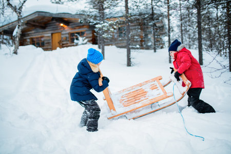 Adorable little girl and cute boy outdoors on Christmas day having fun playing in snow