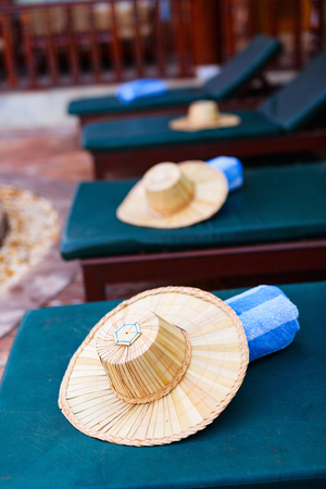 Rolled up towels on sunbeds by beautiful luxury swimming pool at hotel resortの写真素材