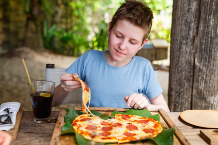 Teenage boy eating pizza for lunchの写真素材