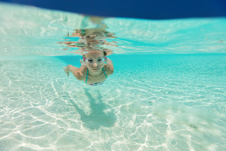 Underwater photo of a little girl swimming in tropical oceanの写真素材